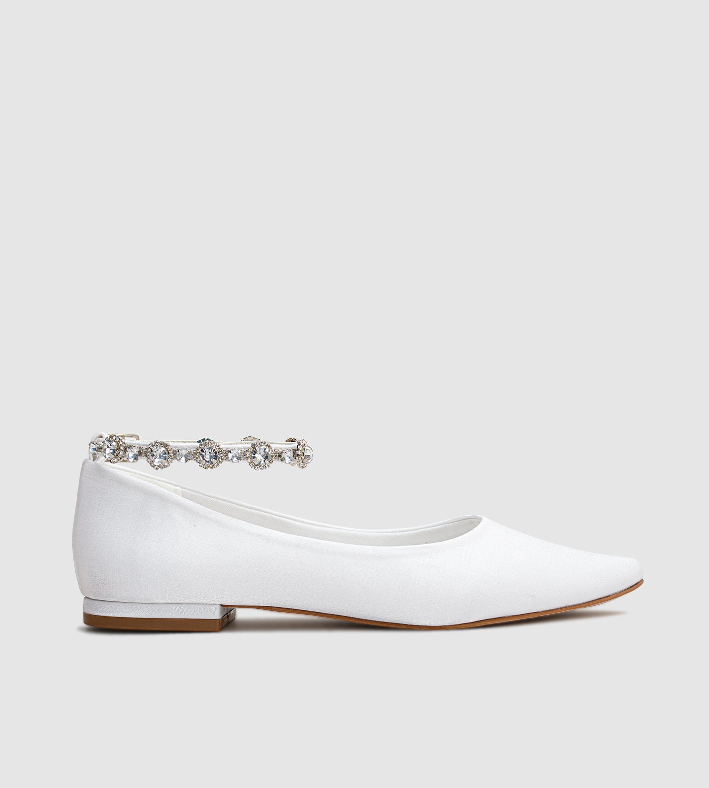 Sapatilha de noiva em material acetinado com acabamento perolado, design minimalista e tornozeleira delicada de strass, ideal para casamentos ao ar livre como no campo ou na praia.