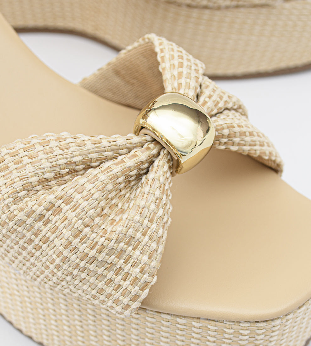 Sandália anabela nude feminina com salto plataforma revestido em palha, tira frontal com nó e fecho de fivela no tornozelo, estilo elegante e confortável para o verão.