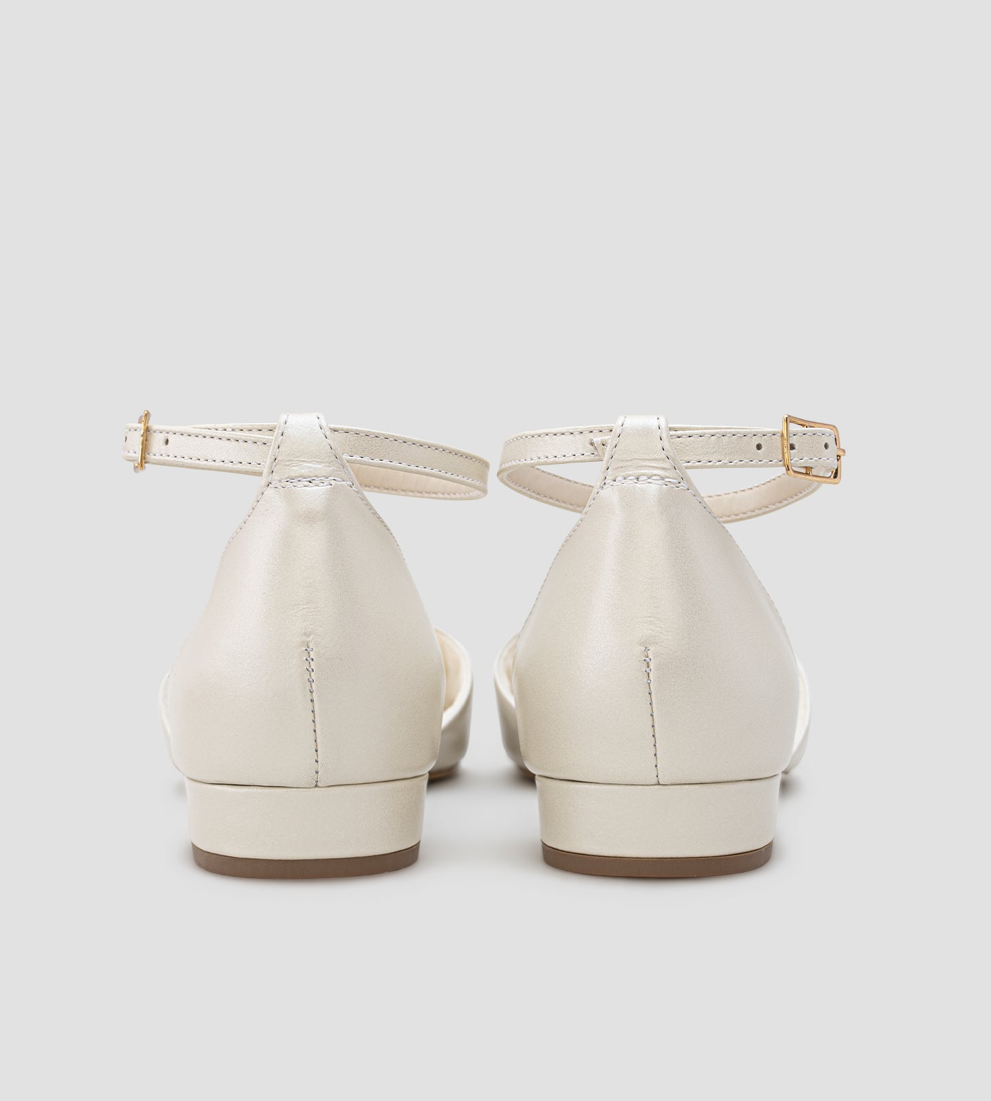 Sandália de noiva estilo sapatilha em couro perolado off white, com bico aberto, tira no tornozelo com fivela e solado baixo, sem salto.