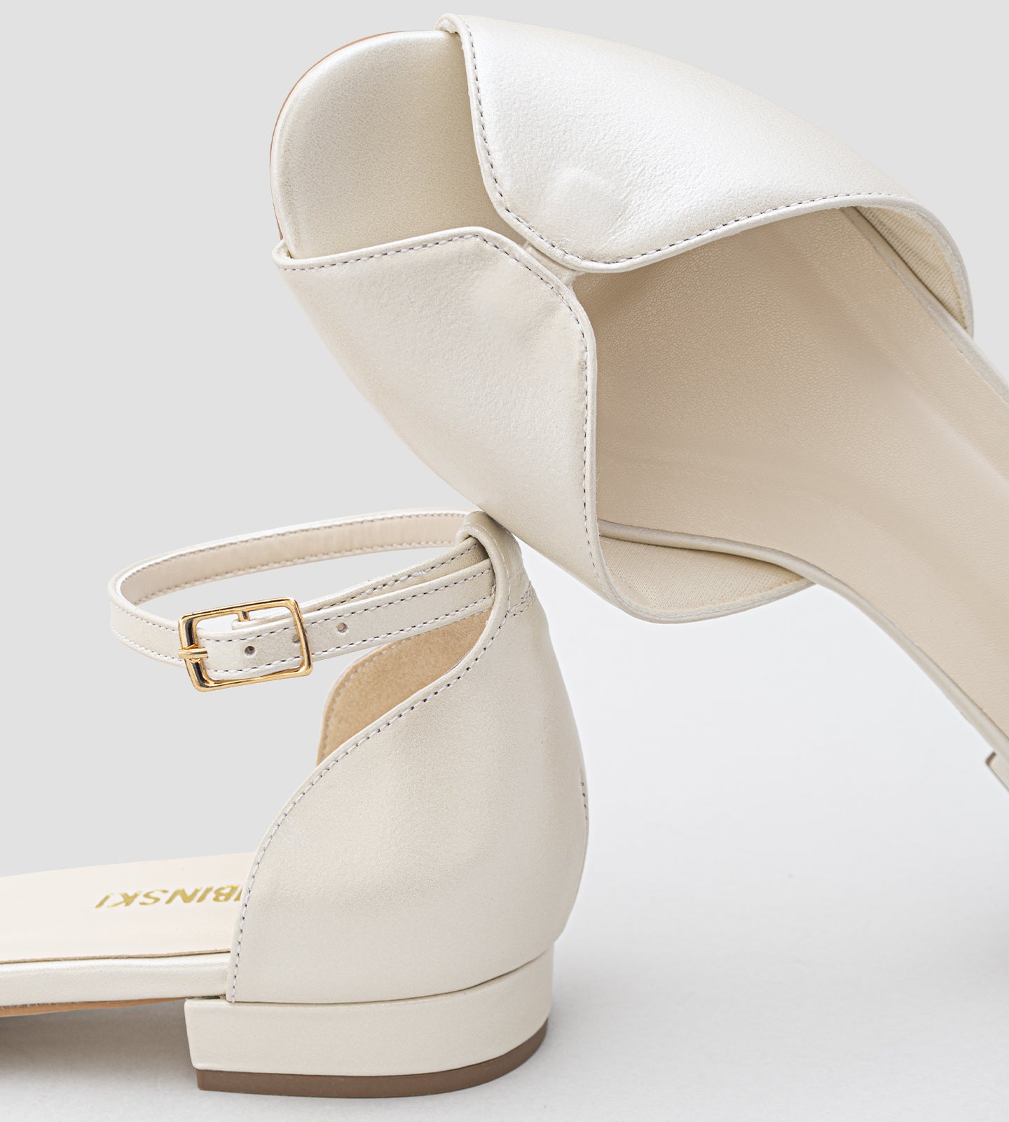Sandália de noiva estilo sapatilha em couro perolado off white, com bico aberto, tira no tornozelo com fivela e solado baixo, sem salto.