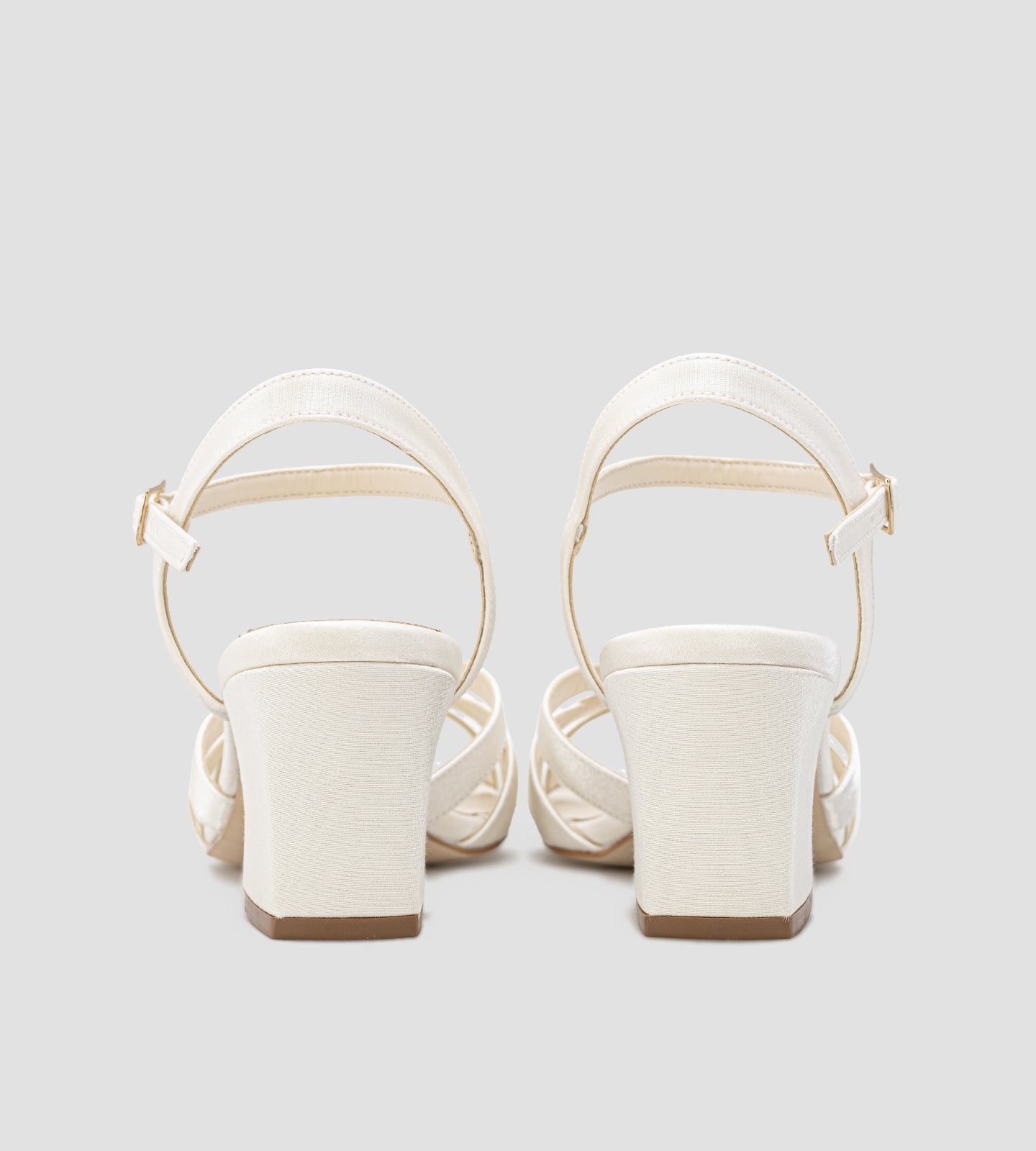 Sandália de noiva em tecido velvet off white, com tiras finas entrelaçadas, salto médio de 7 cm e fechamento no tornozelo com fivela.