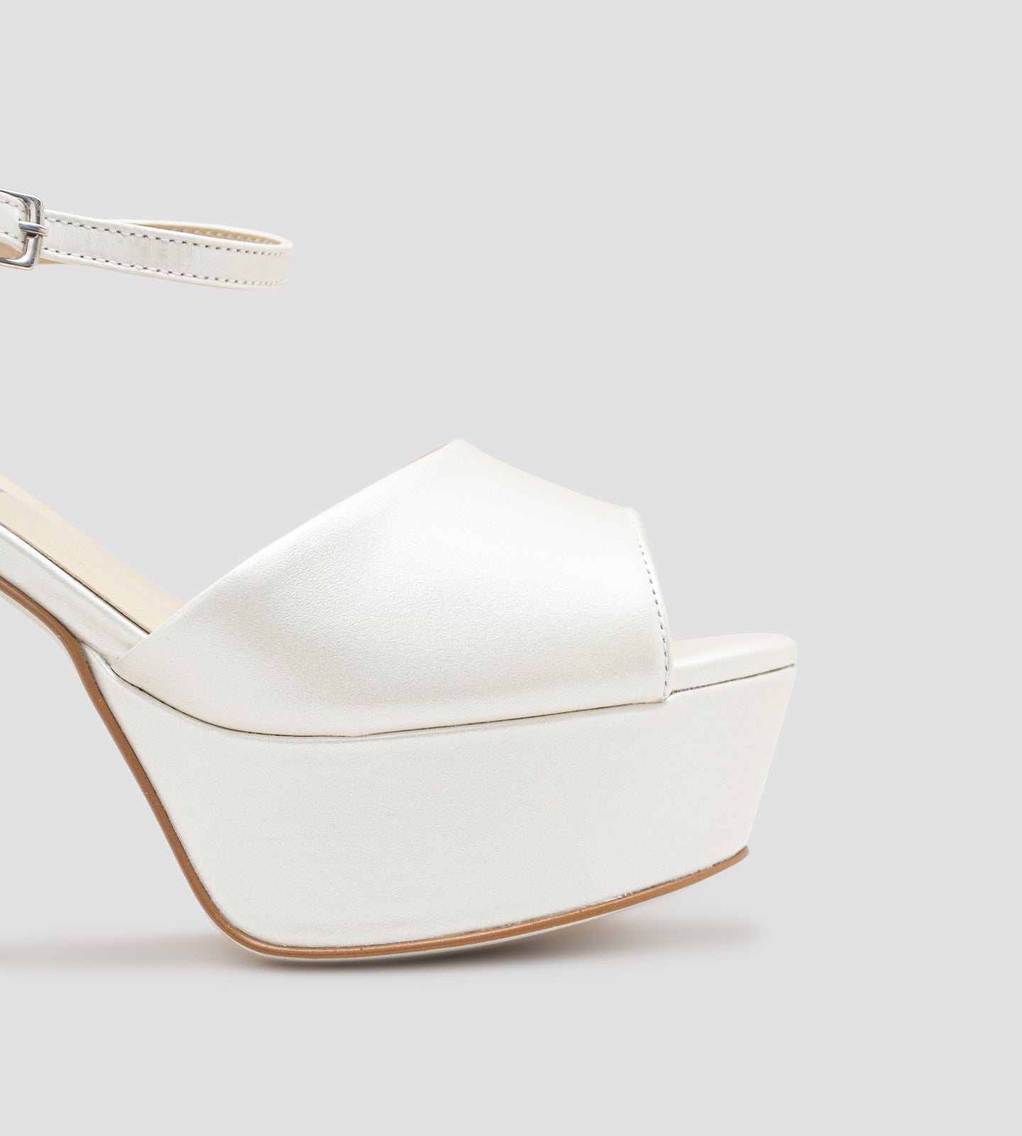 Sandália de noiva em couro perolado off white com plataforma e salto de 10 cm, tira frontal larga e fechamento ajustável no tornozelo.