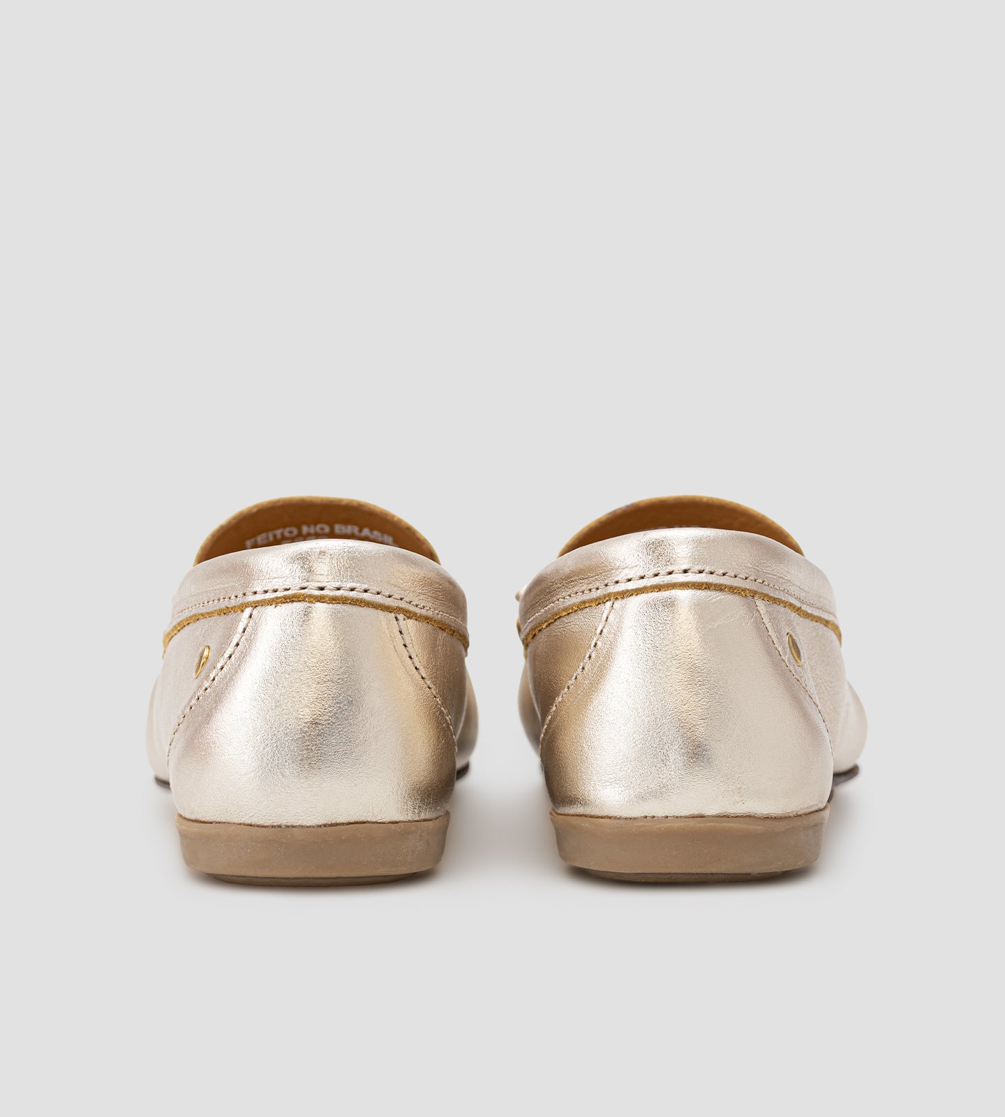 Mocassim feminino em couro legítimo dourado com laço frontal, acabamento sofisticado e design slip-on, ideal para looks elegantes e confortáveis no dia a dia.