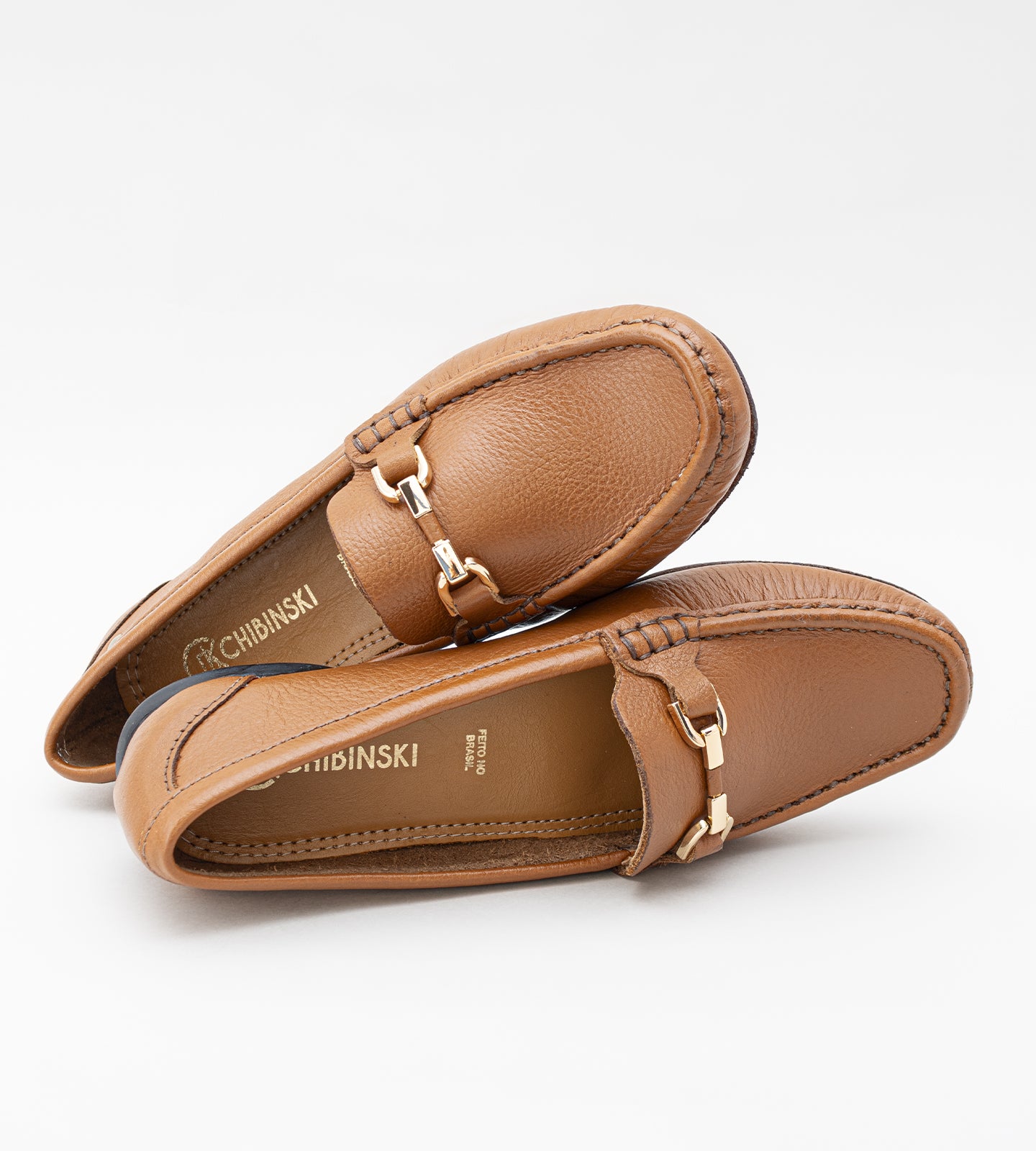 Mocassim feminino em couro marrom com acabamento liso, detalhe metálico no cabedal e solado baixo, design clássico e elegante para uso diário.