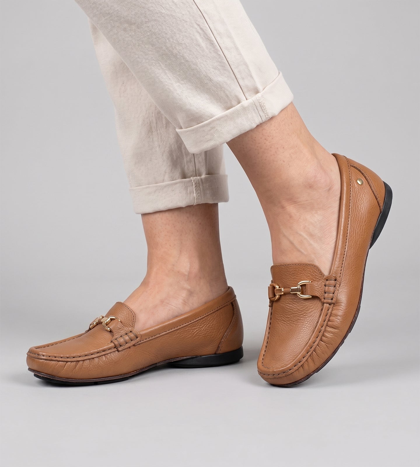Mocassim feminino em couro marrom com acabamento liso, detalhe metálico no cabedal e solado baixo, design clássico e elegante para uso diário.