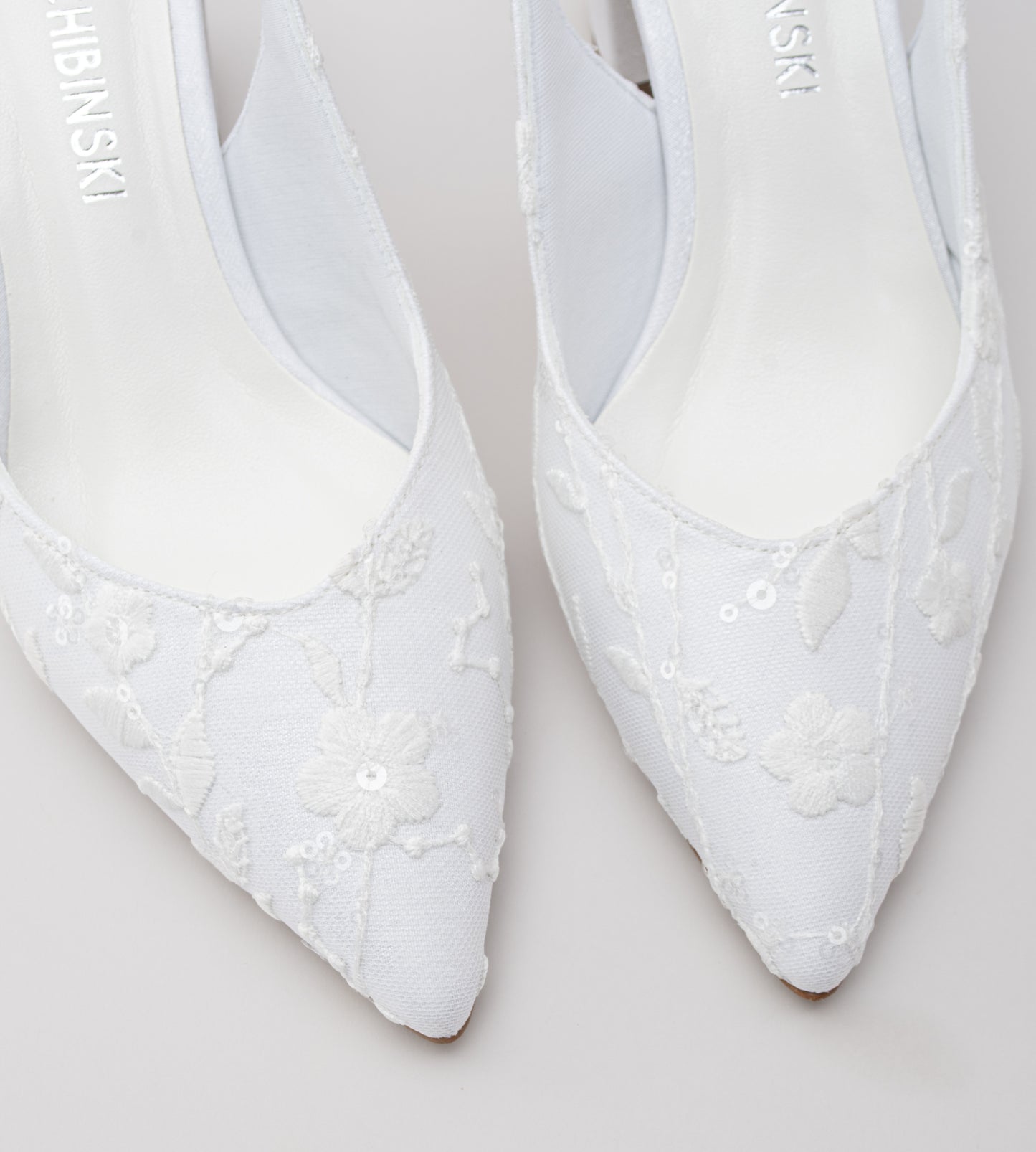 Sapato de noiva slingback em renda branca com flores bordadas, bico fino, salto bloco médio e tira ajustável no calcanhar, ideal para casamentos, combinando elegância, conforto e acabamento artesanal.