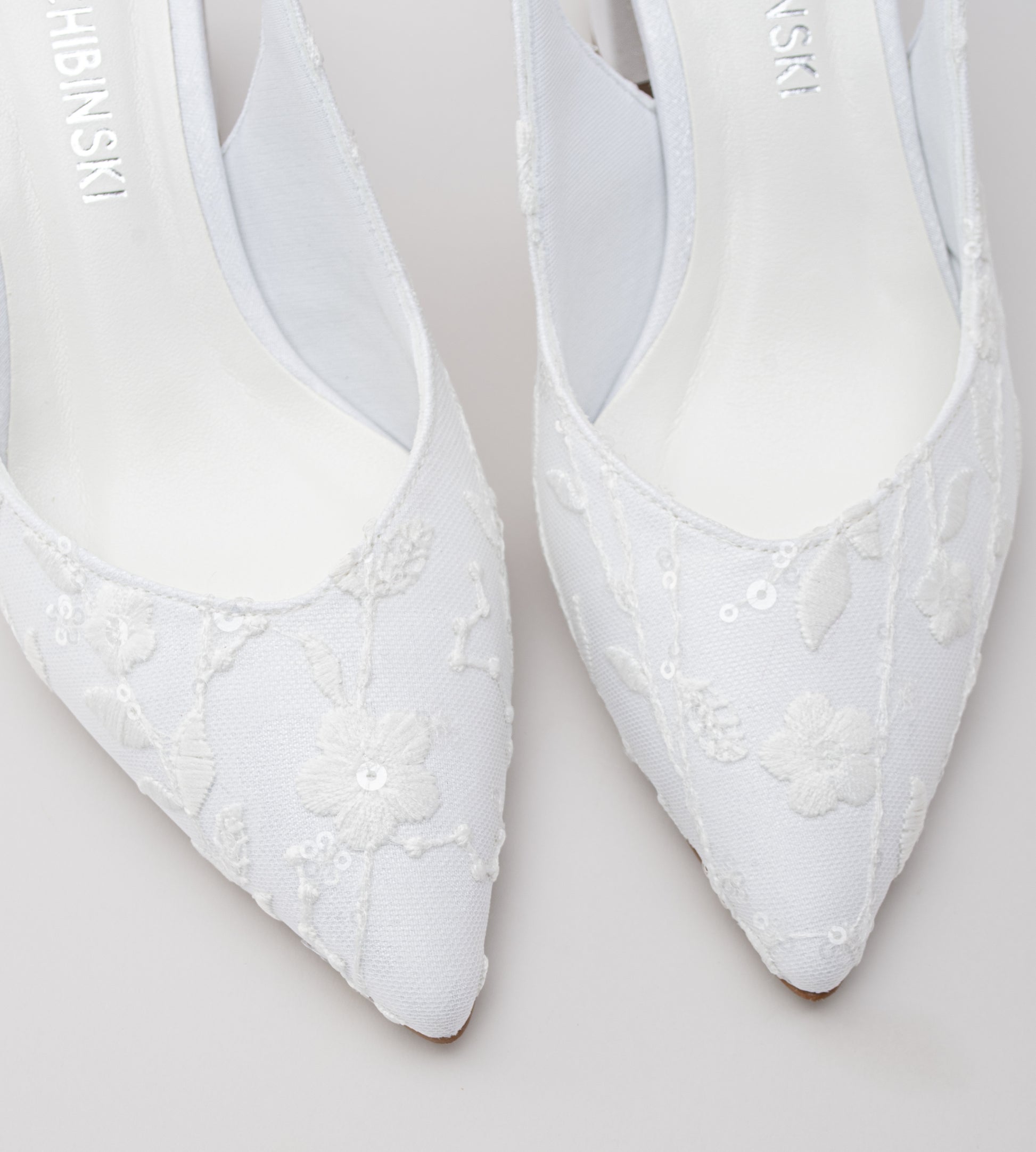 Sapato de noiva slingback em renda branca com flores bordadas, bico fino, salto bloco médio e tira ajustável no calcanhar, ideal para casamentos, combinando elegância, conforto e acabamento artesanal.