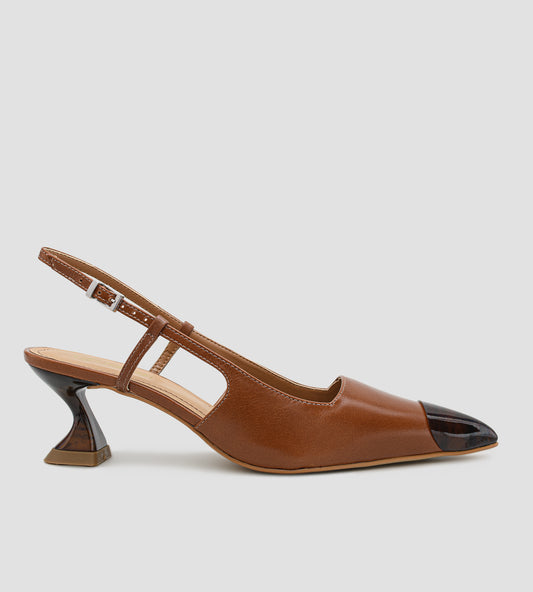 Fotografia de um par de sapatos femininos modelo scarpin slingback na cor caramelo sobre um fundo claro. O calçado possui bico fino com a ponta envernizada em estampa de tartaruga, além de um salto escultural de 6 centímetros com o mesmo padrão de tartaruga. O fechamento é feito por uma tira fina com fivela prateada ajustável no calcanhar.