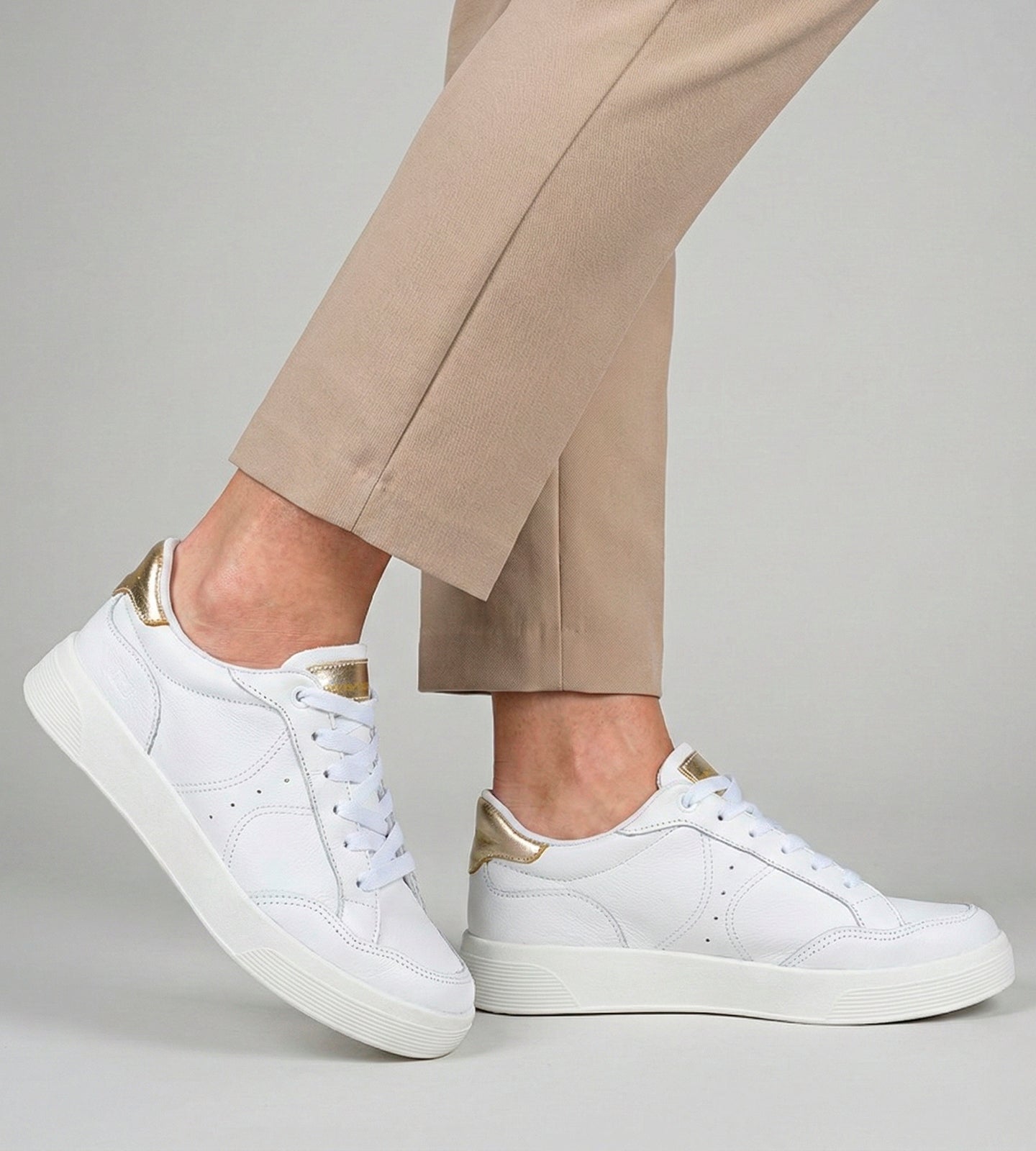 Tênis feminino em couro branco com detalhe dourado no calcanhar, cadarço branco e solado baixo, modelo casual da collab com Marina Mello.