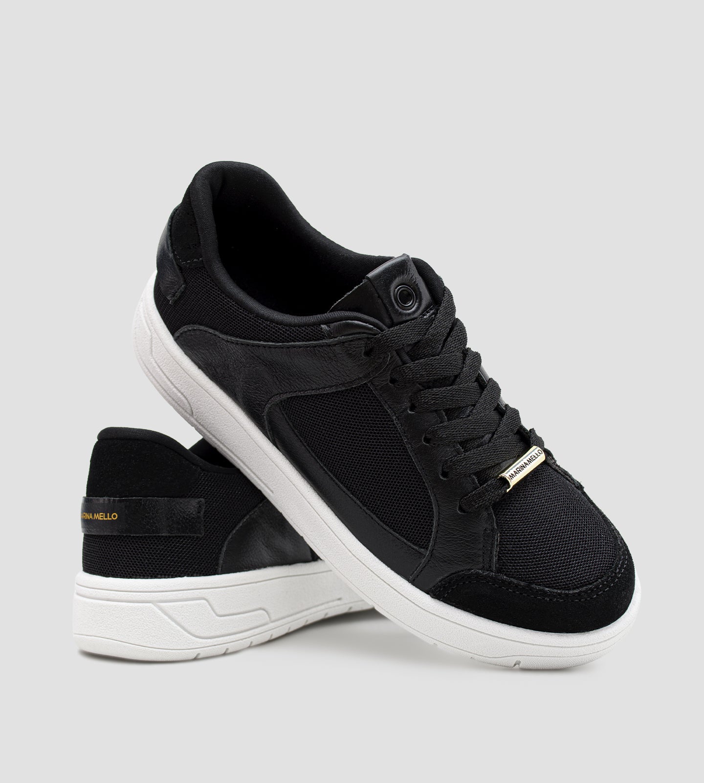 Tênis feminino preto em couro com recortes em tela e suede, solado branco e detalhe Marina Mello no calcanhar, modelo casual com palmilha de gel amortecedor.