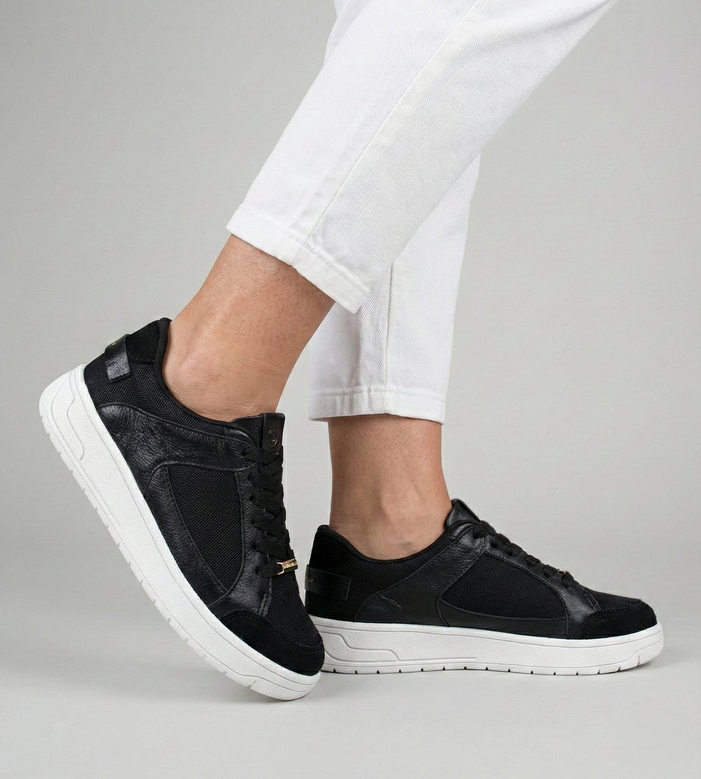 Tênis feminino preto em couro com recortes em tela e suede, solado branco e detalhe Marina Mello no calcanhar, modelo casual com palmilha de gel amortecedor.