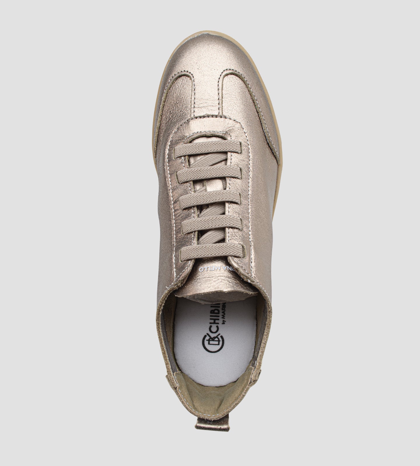 Tênis feminino em couro legítimo dourado metalizado da coleção Chibinski by Marina Mello, com cadarço marrom, solado emborrachado bege e palmilha em gel para maior conforto.