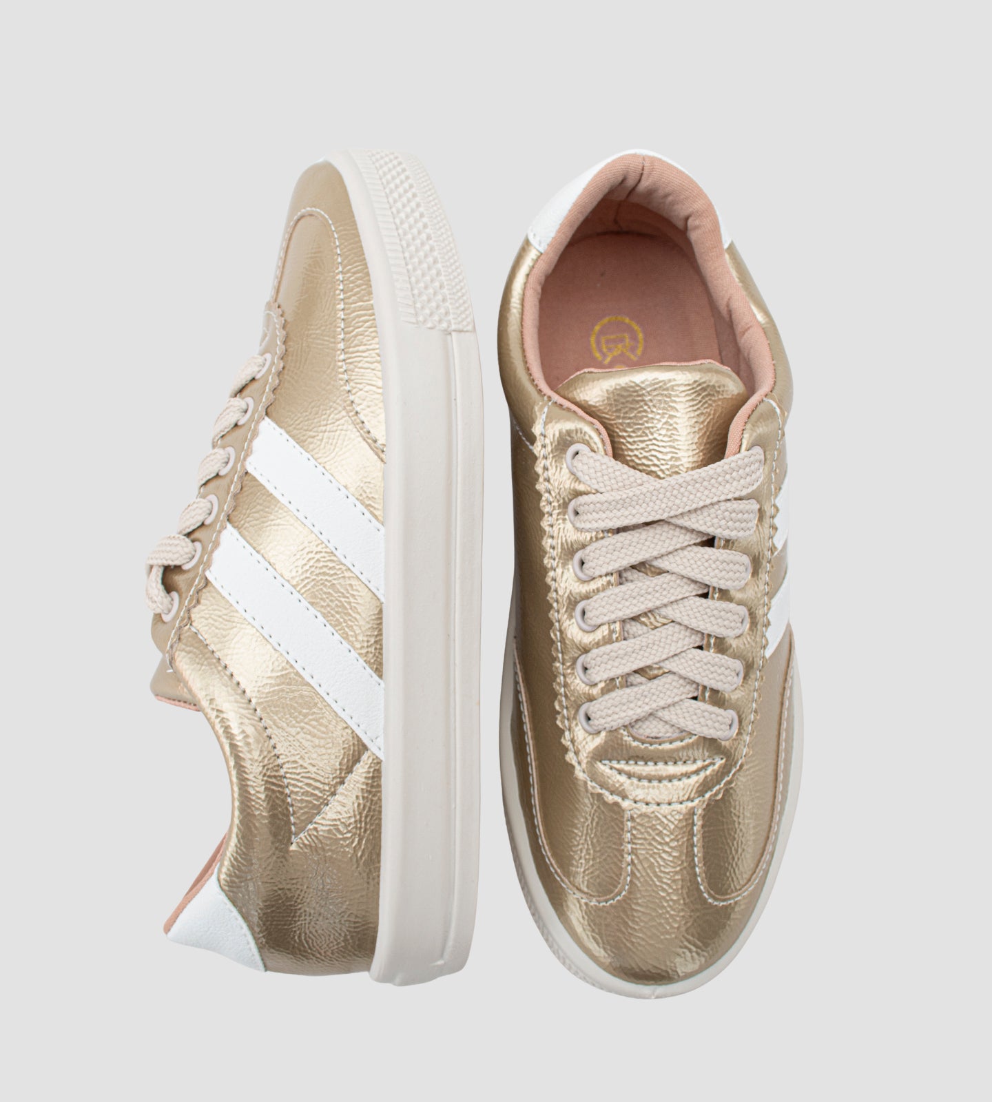 Tênis feminino dourado com acabamento metalizado, listras brancas laterais, cadarço bege e solado branco emborrachado, estilo casual e moderno.