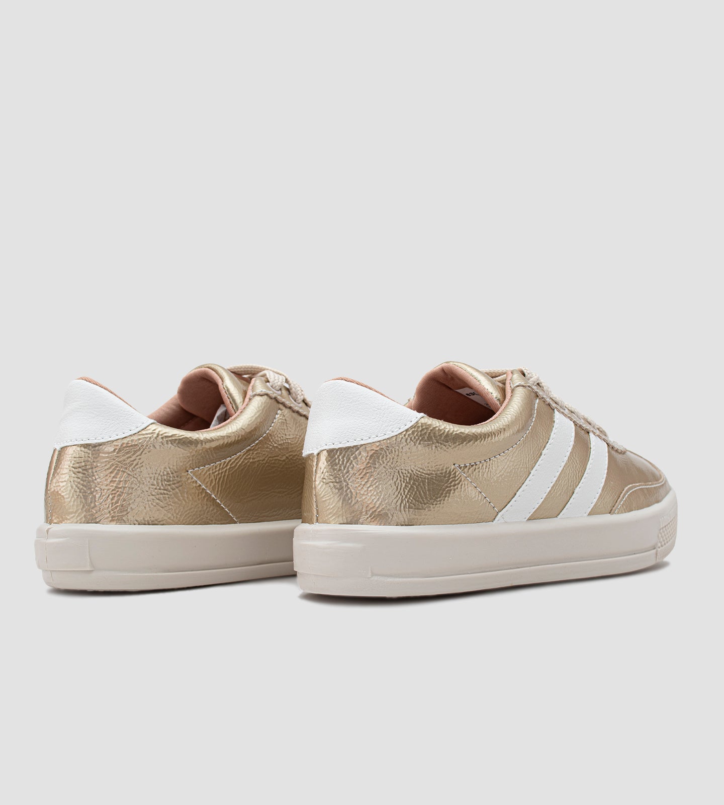 Tênis feminino dourado com acabamento metalizado, listras brancas laterais, cadarço bege e solado branco emborrachado, estilo casual e moderno.