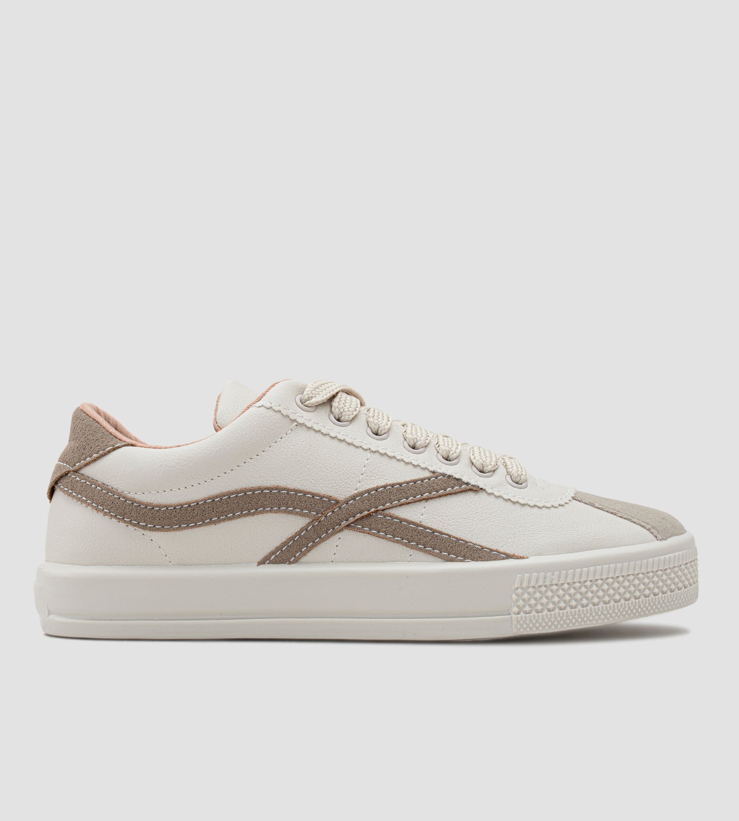 Um tênis casual feminino de cor off-white, com detalhes em bege e um toque sutil de rosa claro, que remete à versatilidade e ao estilo de modelos populares como o Adidas Samba, a silhueta clássica do New Balance 530 e o design consciente dos tênis Veja (anteriormente conhecidos como Vert no Brasil).