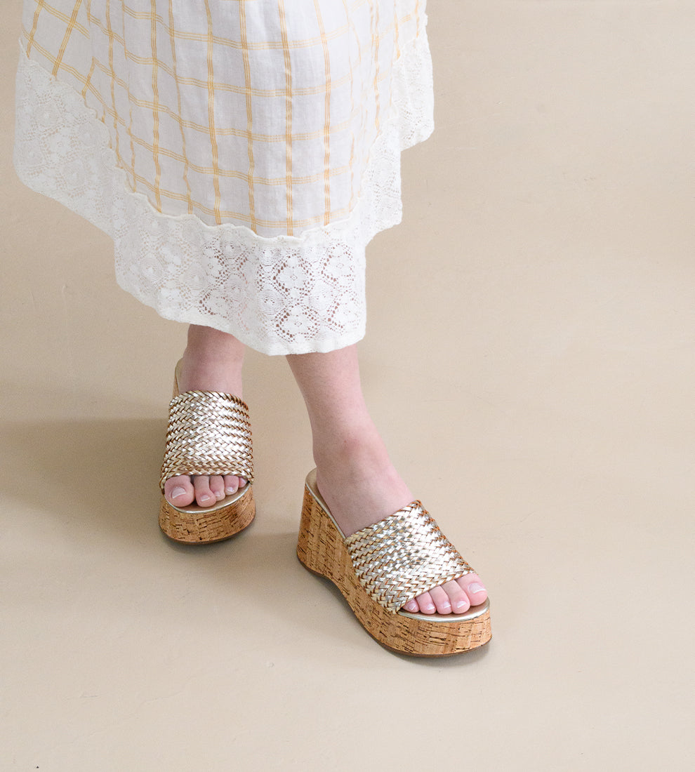 Tamanco feminino dourado com salto plataforma em cortiça e tiras largas trançadas.